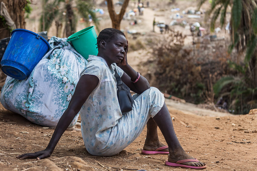 Una mujer descansa junto a su equipaje antes de cruzar el arroyo Kaya cerca de la ciudad de Afoji, distrito de Moyo, en el norte de Uganda