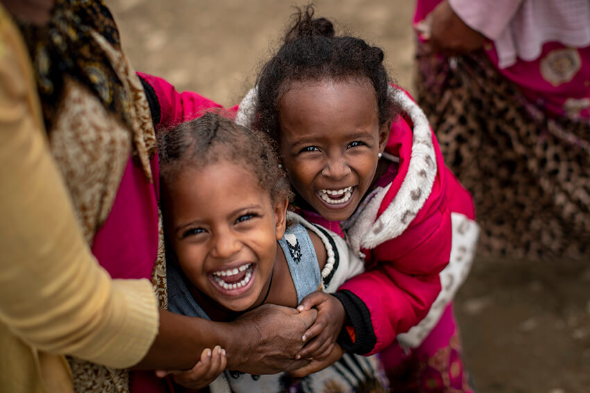 Dos niñas desplazadas ríen junto a su madre, a la izquierda, mientras se les toma una fotografía en el exterior de la Escuela Secundaria General de Hadnet, que se ha convertido en un hogar improvisado para miles de personas desplazadas por el conflicto, en Mekele, en la región de Tigray, en el norte de Etiopía, el 5 de mayo de 2021.