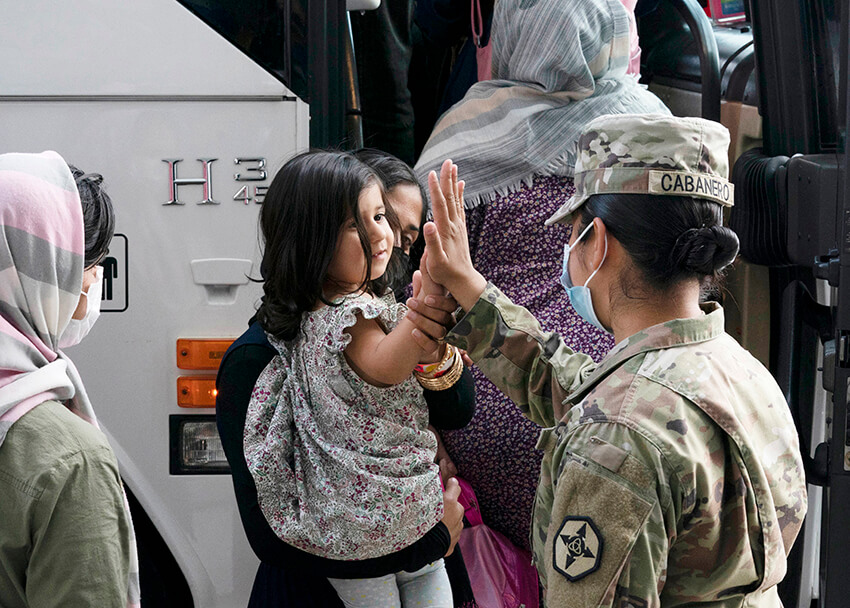 La soldado del ejército estadounidense choca los cinco con una niña evacuada de Kabul, Afganistán, antes de subir a un autobús tras su llegada al aeropuerto internacional de Washington Dulles, en Chantilly, Virginia, el 30 de agosto de 2021. 