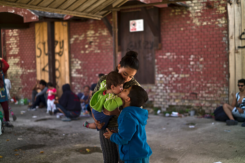 Mohammed Abdulkarim, de 6 años, alcanza a besar a su hermano Zain, de 6 meses, mientras es sostenido por su hermana Laila, de 13. Están en la estación de tren de Beli Manastir, al noreste de Croacia, cerca de la frontera con Hungría. 