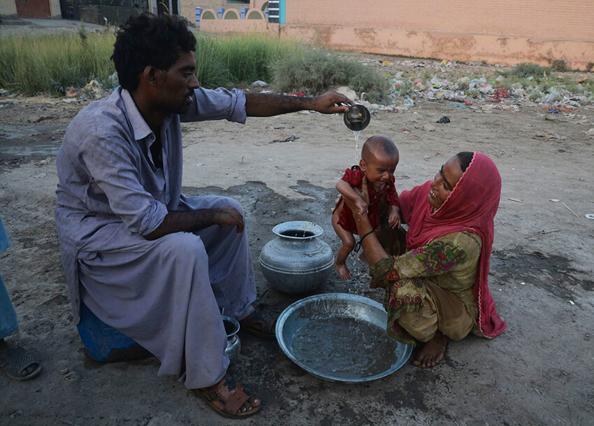 Una familia refresca a su bebé con un poco de agua