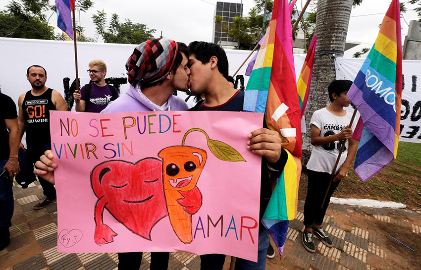 Los participantes se besan durante el "Kissathon", un evento organizado por grupos activistas para celebrar el Día Internacional contra la Homofobia frente al Congreso en Asunción, Paraguay, el 17 de mayo de 2017. El cartel dice: "No se puede vivir sin amor".