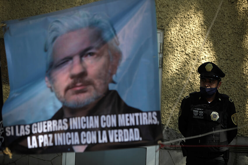 Un oficial de policía se encuentra junto a una pancarta que muestra al fundador de WikiLeaks, Julian Assange. El gobierno de México se mostró dispuesto a ofrecer asilo político a Assange y apoyó la decisión de un juez británico de negar la extradición del fundador de WikiLeaks a los Estados Unidos, el 4 de enero de 2021. El texto dice: "Si las guerras se pueden declarar con mentiras, la paz se puede iniciar con la verdad". 