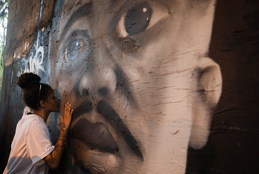 itoria, hija de Marcelo Guimaraes (que según los vecinos fue asesinado a tiros por la policía mientras conducía una motocicleta junto a la favela Cidade de Deus), besa un grafiti pintado en su honor durante una protesta contra su muerte en el lugar donde le dispararon en Río de Janeiro, Brasil, 5 de enero de 2021.