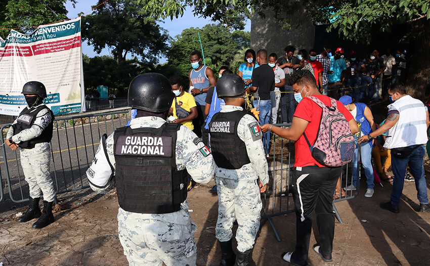 Miembros de la guardia nacional vigila a migrantes haitianos