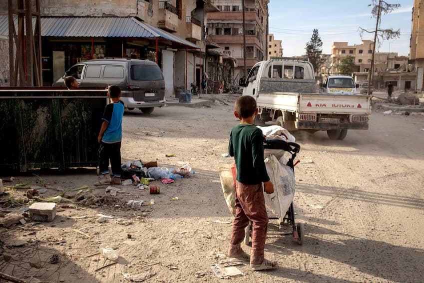 Niños en Raqqa, Siria, rodeados de destrucción tras crímenes de guerra documentados durante el conflicto.