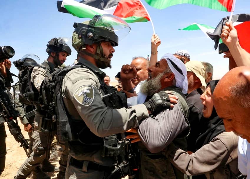 Un anciano palestino se enfrenta a un miembro de las fuerzas israelíes mientras varios activistas se manifiestan contra el desalojo de aldeas palestinas