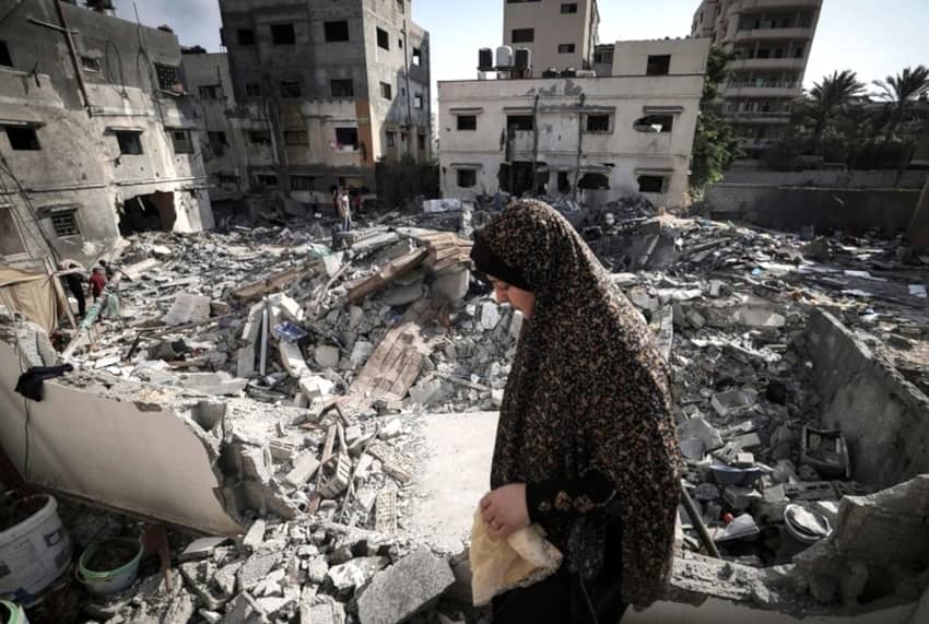 Una mujer palestina comprueba los daños mientras camina entre los escombros frente a su casa en la ciudad de Gaza