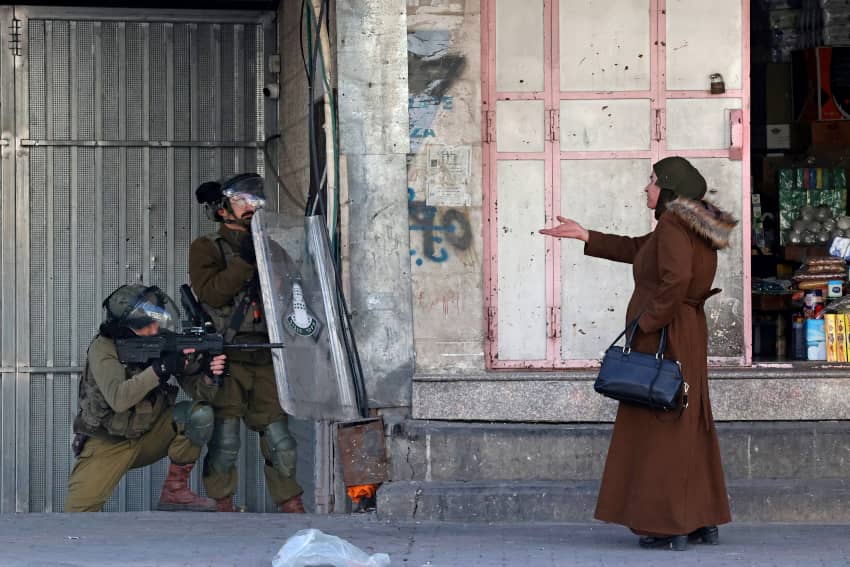 Una mujer señala a las fuerzas de seguridad israelíes que disparan balas de goma para dispersar a los palestinos que lanzaban piedras en medio de enfrentamientos en la ciudad cisjordana de Hebrón, el 9 de febrero de 2022. Amnistía Internacional revela las protestas más impactantes de 2022 en su informe anual