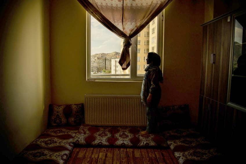 Una mujer mira por una ventana. Las mujeres afganas no pueden salir a la calle si no van acompañas de un mahram. Esta es otra de las restricciones impuestas por los talibanes