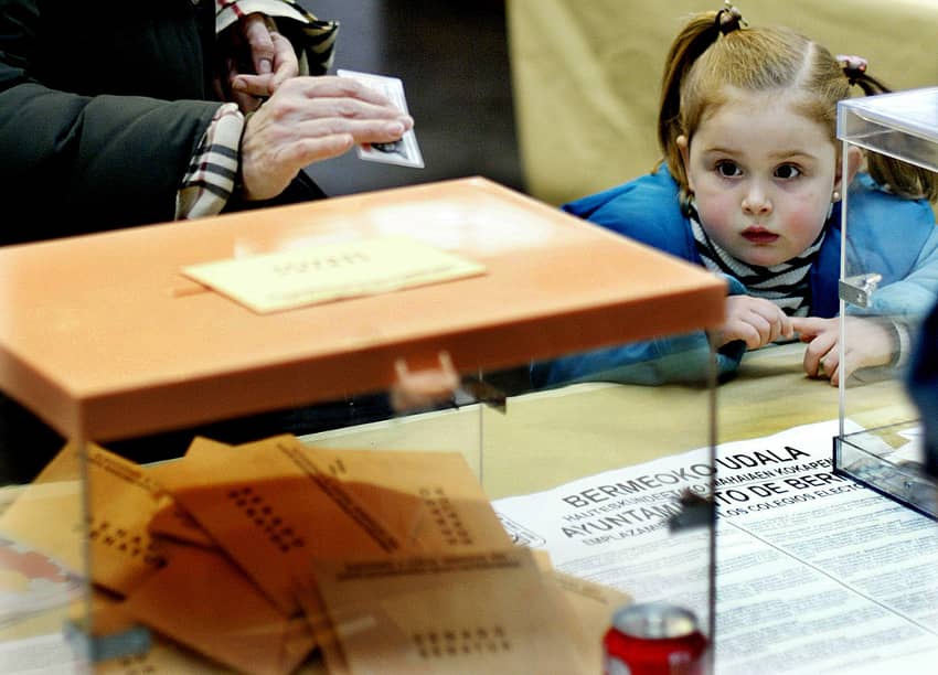 Una niña mira mientras su madre deposita su voto en las elecciones generales celebradas en España