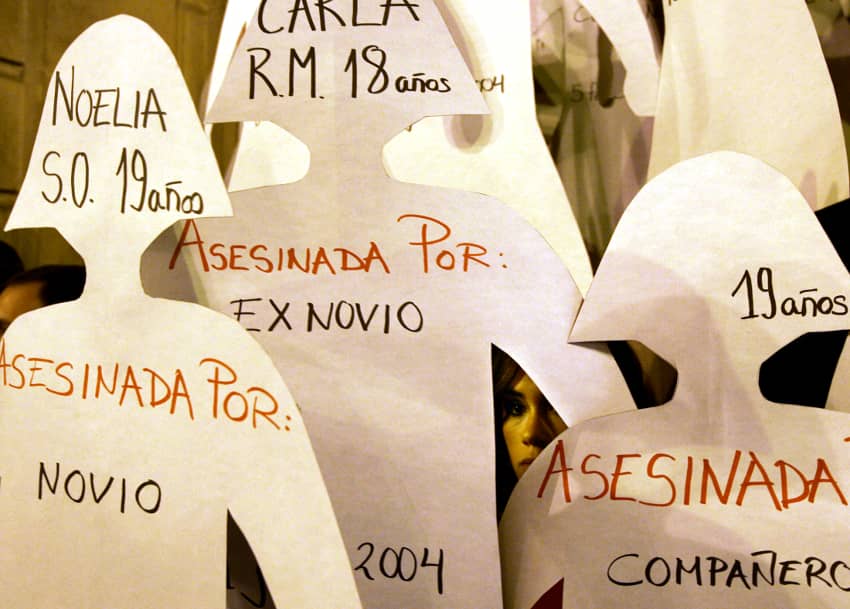 Unas manifestantes sostienen grandes muñecas de papel con nombres de mujeres asesinadas por sus parejas durante una manifestación contra la violencia de género en Sevilla