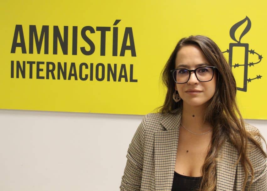 Primer plano de Clara del Campo con el logo de Amnistía Internacional de fondo
