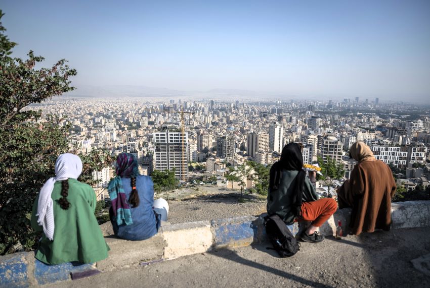 Unas chicas jóvenes iráníes con el velo puesto contemplan un atardecer