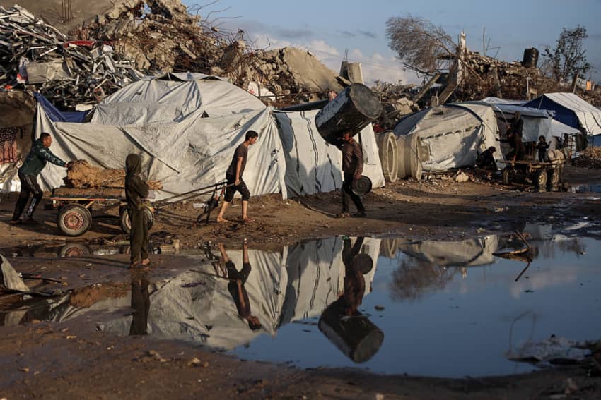 Hombre palestino desplazado caminando con un carro bajo fuertes lluvias en Jabalia, Gaza, noviembre de 2025.