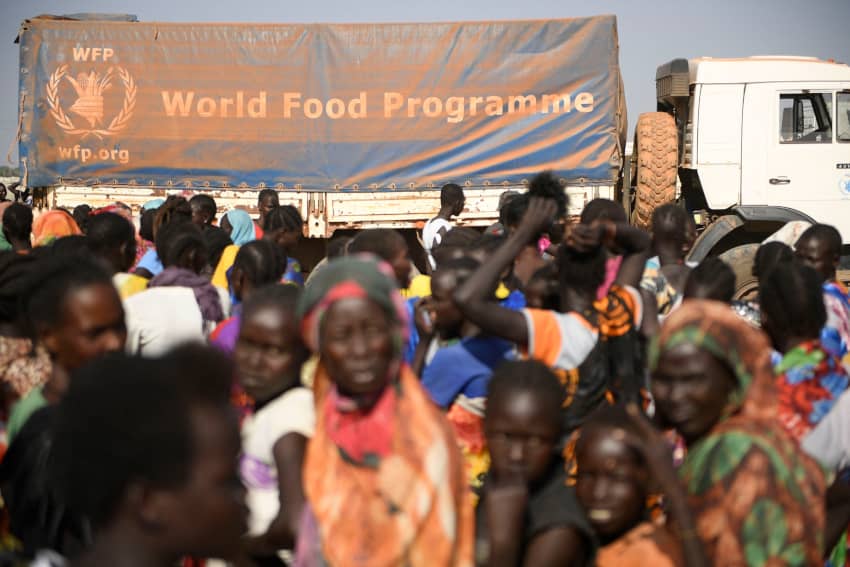 Grupo de mujeres desplazadas internas hace fila para recibir alimentos junto a un camión del Programa Mundial de Alimentos