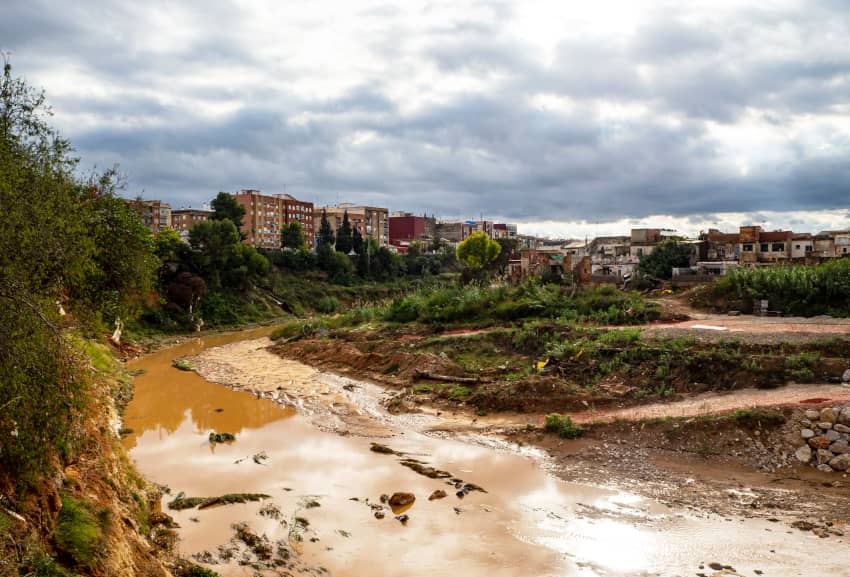 Cauce del barranco en Torrent con agua turbia y viviendas próximas afectadas por la DANA de 2024