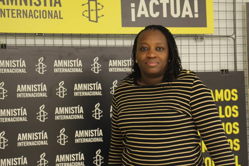 Flavia Mwangovya frente al logotipo de Amnistía Internacional durante su visita a España para hablar sobre Sudán, conflictos en África y derechos humanos.