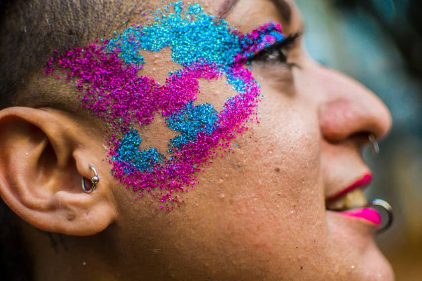 Primer plano de persona con maquillaje inspirado en la bandera trans durante una celebración del Orgullo