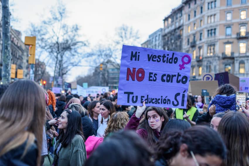 Joven sostiene un cartel que dice “Mi vestido no es corto, tu educación sí” durante una manifestación del Día Internacional de las Mujeres en Barcelona.