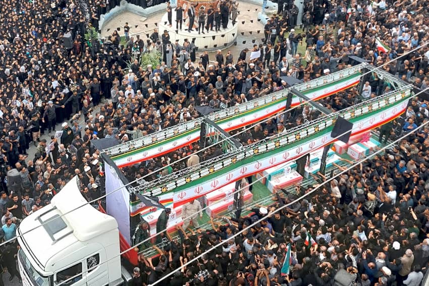 Vista aérea de una multitud en Teherán acompañando féretros cubiertos con la bandera iraní durante un funeral por víctimas de un bombardeo a una escuela en Minab.