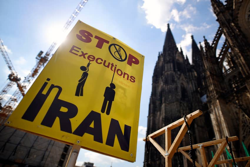 Manifestación contra la pena de muerte en Irán con cartel “Stop Executions” y horcas simbólicas