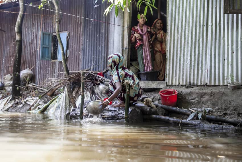  Mujer trabaja entre aguas de inundación frente a su casa en Bangladesh.