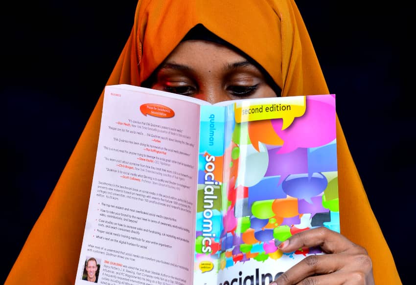 Mujer con hiyab naranja leyendo un libro