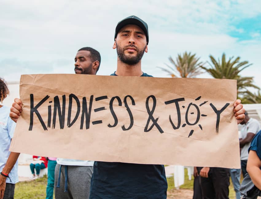 Manifestante sostiene un cartel “Kindness & Joy” en una protesta contra la violencia.